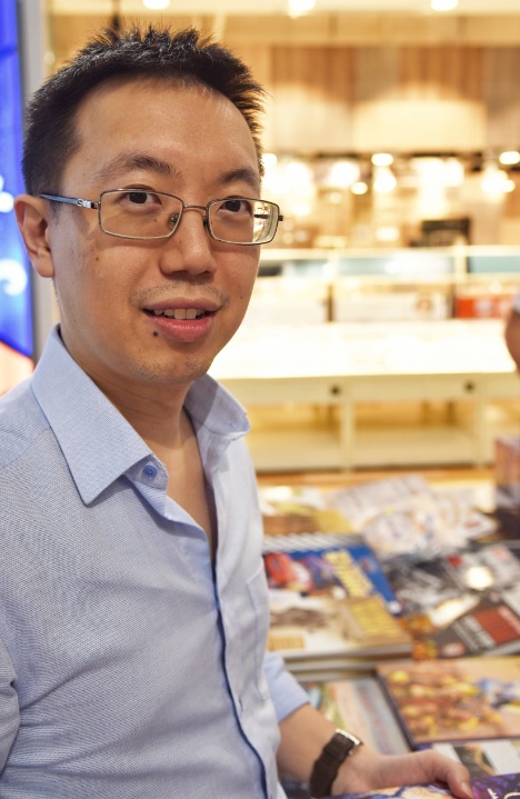 Author and speaker Shawn Seah standing with books. 