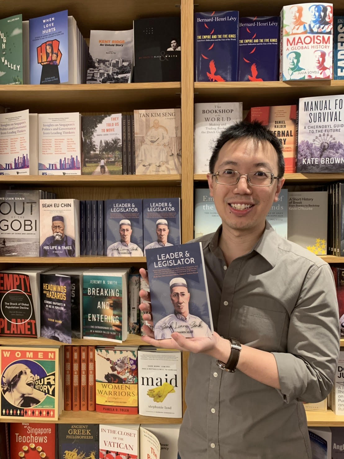History and heritage author Shawn Seah standing at Kinokuniya holding up a copy of his book.